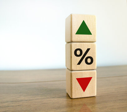 Interest rates symbol. Wooden cubes with the direction of an arrow symbolizing that the interest rates are going down or up. Beautiful wooden table, white background. Business concept. Copy space.