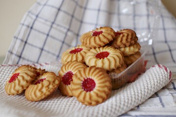 sand cookies with jam in the middle on a napkin and in a plastic box