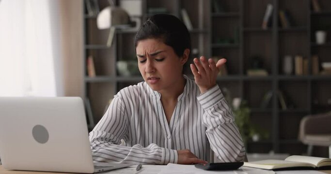 Unhappy frustrated young indian ethnicity woman calculating expenditures or taxes, feeling stressed of mistakes or lack of money indoors, financial problems, bank loan debt, accounting concept.