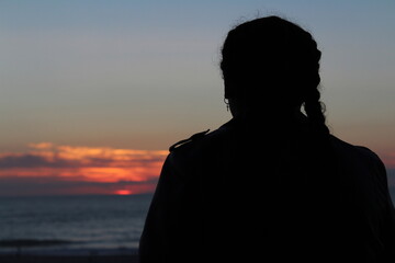 Fototapeta premium Silhouette of a person looking at the sunset on the ocean 