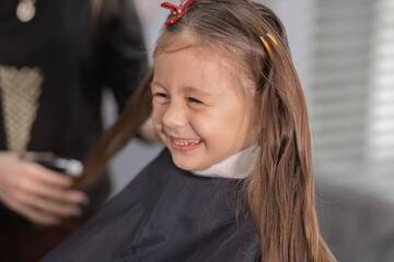 hairdressing salon. Hairdresser girl doing hairstyle to a little girl