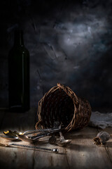 Old spoons and forks scattered on a wooden table near a wicker basket
