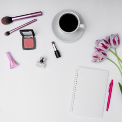 top view of feminine cosmetics, coffee and blank notebook on white background