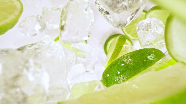 Super Slow Motion Shot of Lime Slices and Ice Cubes Falling on Black Background at 1000 fps.