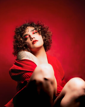 Mujer  pelo rizado en fondo rojo con tatuajes