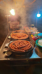 Thai style grilled round sausages on a stove In street food at night