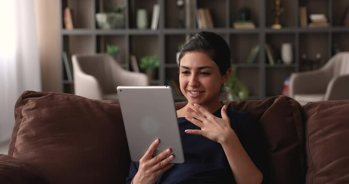 Smiling pleasant beautiful indian ethnicity woman holding tablet in hands, holding web camera video call meeting with friends, communicating distantly with family, talking chatting sharing life news.
