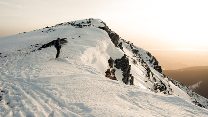 Skier skinning uphill on a hot sunny day. Very attractive sport. Background of snow-capped...