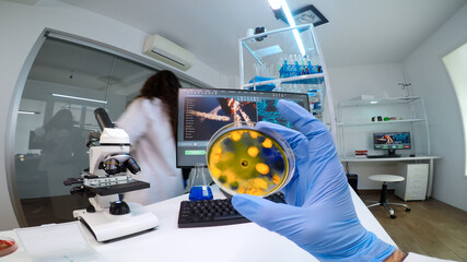 Doctor examining petri dish with various bacteria analysing virus evolution working in equipped...