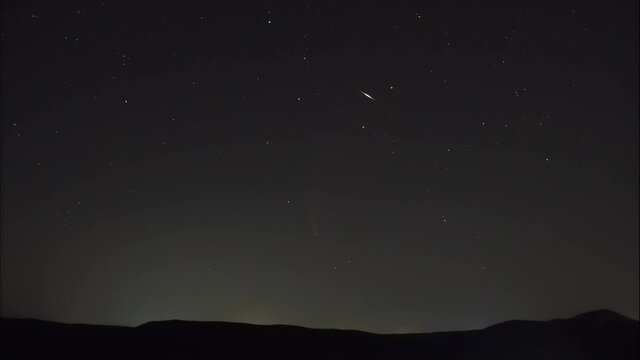 Night time laps. A comet in the night sky among the stars and meteorites over the ridge.