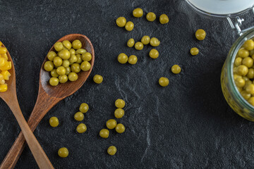 Canned sweet corn seeds and green olives on black background