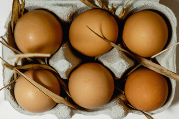 Chicken eggs in a paper tray on a grass straw. top view