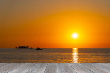 Fototapeta na wymiar grey wooden aged terrace floor with blurred orange ocean sunset background