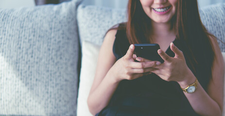 woman holding mobile phone and smile on sofa