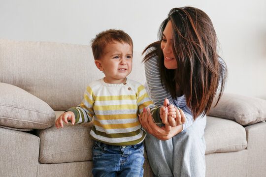 Portrait Of Adorable Little Boy Sitting On The Textile Couch With His Mom And Crying. Upset Toddler Throwing A Tantrum At Home. Barefoot Calling For Attention. Close Up, Copy Space, Background.