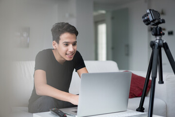 Young boy talking online using laptop and camera equipment