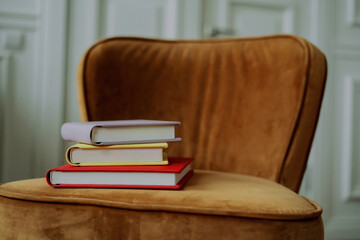On a red-colored chair, memories are stored. Stylish books with important events. A stack of photo book albums with photos of different colors.