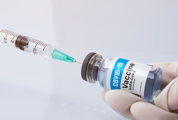 Close up, Hand holding Covid-19 Vaccine bottle and taking the liquid vaccine from it with a syringe