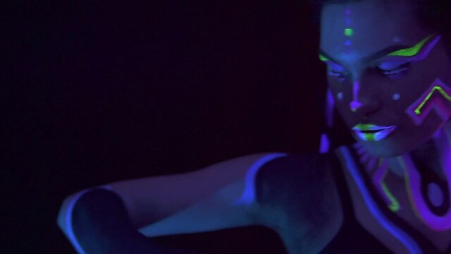 Portrait of a Girl with Dreadlocks in Neon UF Light. Model Girl with Fluorescent Creative Psychedelic MakeUp, Art Design of Female Disco Dancer Model in UV, Colorful Abstract Make-Up. Dancing Lady