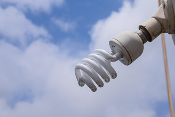 Picture of Installed white CFL bulb on cloudy blue sky background.eco ,energy saving bulb.