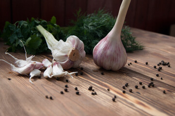 Garlic, spices and herbs on a wooden background.