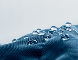 Water drops on waterproof membrane fabric. Detail view of texture of blue waterproof cloth.