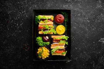 Sandwich with cutlet, cheese and lettuce on a black stone background. Street food. Top view. Free copy space.