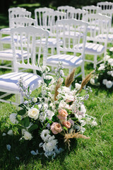 White chairs lined up for wedding ceremony. flower composition, decoration