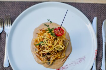 White plate with gourmet snack and a piece of meat.