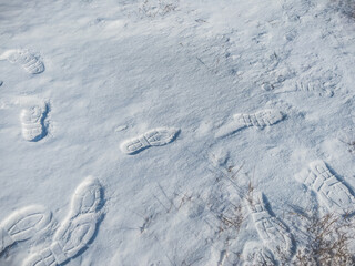 Close up of footprints on white snow. Human footmarks of unknown people on ground with precipitation in winter season.