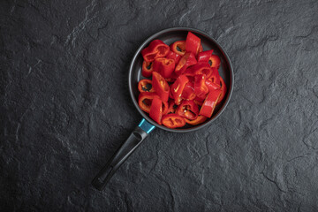 Black pan of sliced red bell peppers on black background