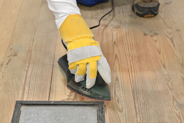Carpenter's hand sanding with electrical sander