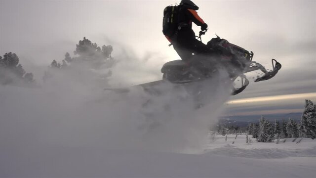 SLOW MO: video footage of jumping snowmobilers at sunset. the snowmobile flies through the air and creates large and beautiful swirls of snow. ProRes 422. HD 500fps