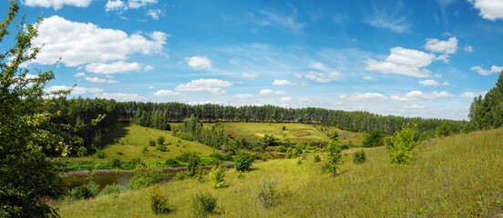 Beautiful panoramic view and landscape with green hills and green woods during sunny summer day.