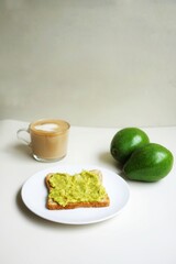Avocado toast, americano coffe, and latte on a white table
