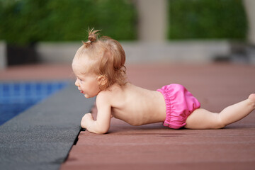 Little baby girl near swimming pool outdoors.