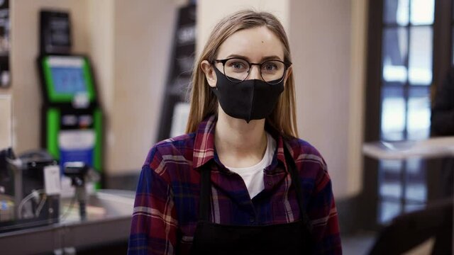 Portrait of a woman in a medical mask working at the checkout in a supermarket