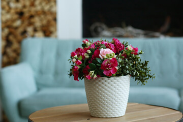 modern bedroom closeup fragment with flowers in vase, sofa and pillows on background