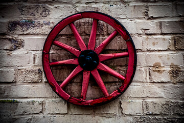 Red and old wooden wheel on the stone wall