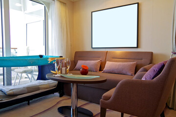 Living room of balcony suite cabin stateroom in clean modern cozy interior design with desk, arm...