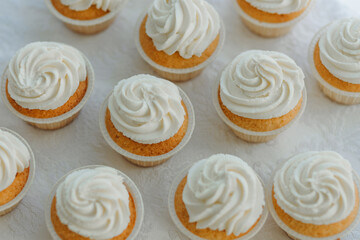 Delicious vanilla cupcakes with cream cheese frosting, white background, selective focus.
