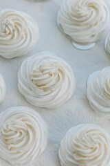 White zephyr in white plate on a white background with copy space. Baking for a bakery, coffee shop or sweet shop. French vanilla meringue cookies.