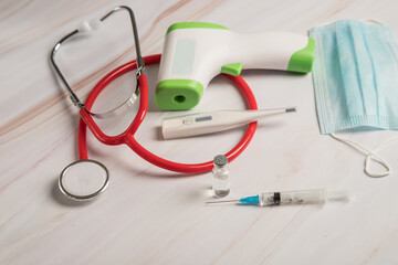 Medical equipment consisting of a stethoscope, an infrared and electronic thermometer, a protective medical mask , a syringe and a bottle of coronavirus vaccine.