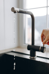 Woan is opening and closing water flow tap and filling sink with water. Water running from chrome...