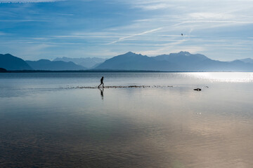 Silhouette einer Person im Chiemsee im  Fr&uuml;hling mit Bergen im Hintergrund