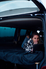 Beautiful blonde woman lying on the bed with gray aluminum laptop.