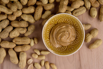 Peanuts and peanut butter in a jar on the table top view stock images. Pile of peanuts and bowl of peanut butter stock photo. Peanuts on a wooden background top view