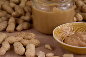 Peanuts and peanut butter in a jar on the table close-up stock images. Pile of peanuts and a glass of peanut butter on a wooden background detail stock photo