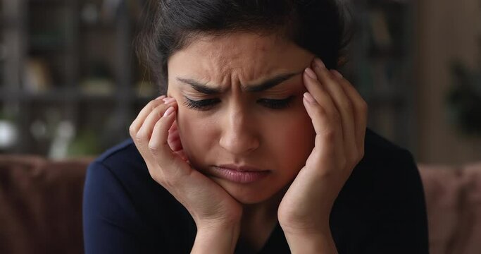 Close up frustrated worried unhappy millennial mixed race indian woman frowning, suffering from negative thoughts or headache, feeling doubtful thinking of difficult decision, depression concept.