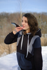 Young fitness trainer in dark sportswear is sending audio voice message explaining something on...